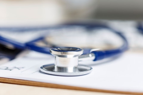 Prescription form clipped to pad lying on table with stethoscope. Medicine or pharmacy concept. Empty medical form ready to be used